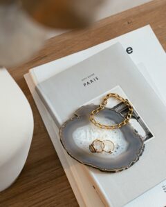 Stylish flat lay featuring gold jewelry on an agate tray with a Paris city guide, capturing modern elegance.