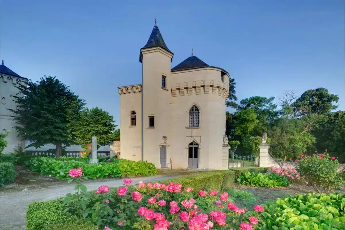 Gotischer Turm des Château de Candes im Loire-Tal mit blühendem Rosengarten im Vordergrund in der Abenddämmerung