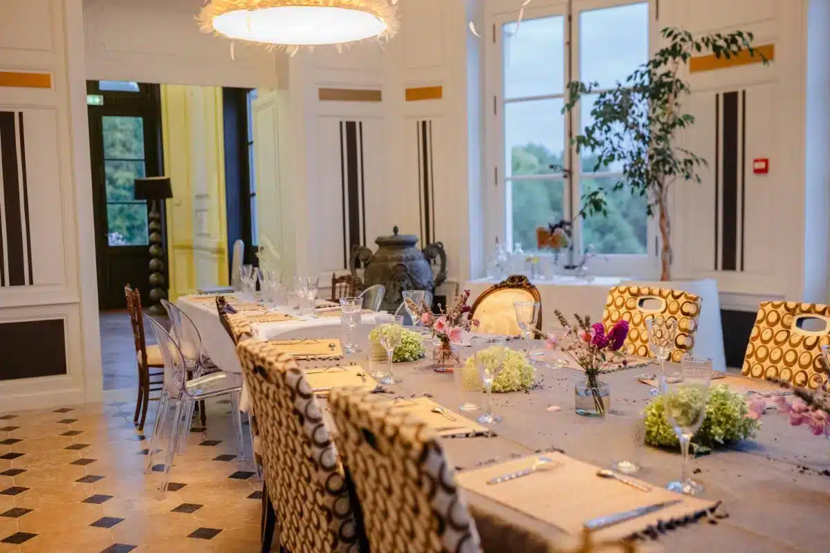 Eleganter privater Speisesaal im Château de Candes im Loire-Tal, eingedeckt für ein festliches Dinner mit goldgemusterten Stühlen, Kristallgläsern und Blumenarrangements