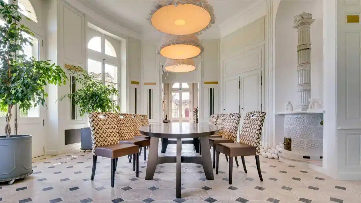 Lichtdurchfluteter Speisesaal im Château de Candes im Loire-Tal mit großen Bogenfenstern, Schachbrettfliesen und zeitgenössischen Designer-Sesseln