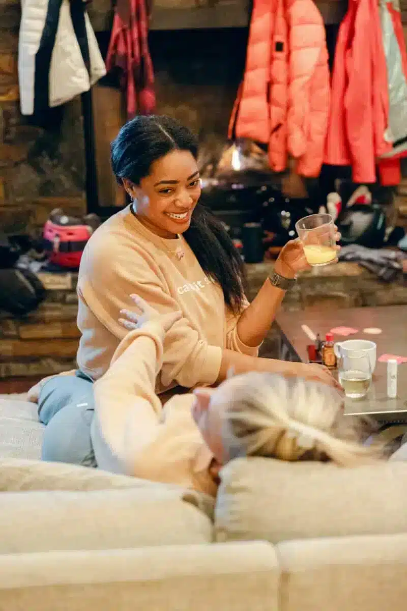 Two guests relaxing indoors in a cozy après-ski setting with warm drinks and candlelit atmosphere at The Retreat Company