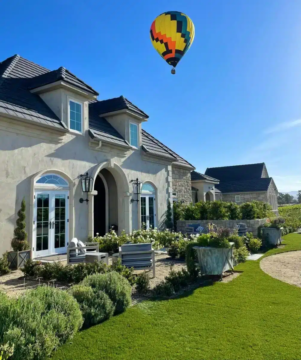 Französisch inspirierte Fassade von Domaine Chardonnay in Temeculas Weinregion mit einem bunten Heißluftballon über dem gepflegten Garten und der Gästeterrasse