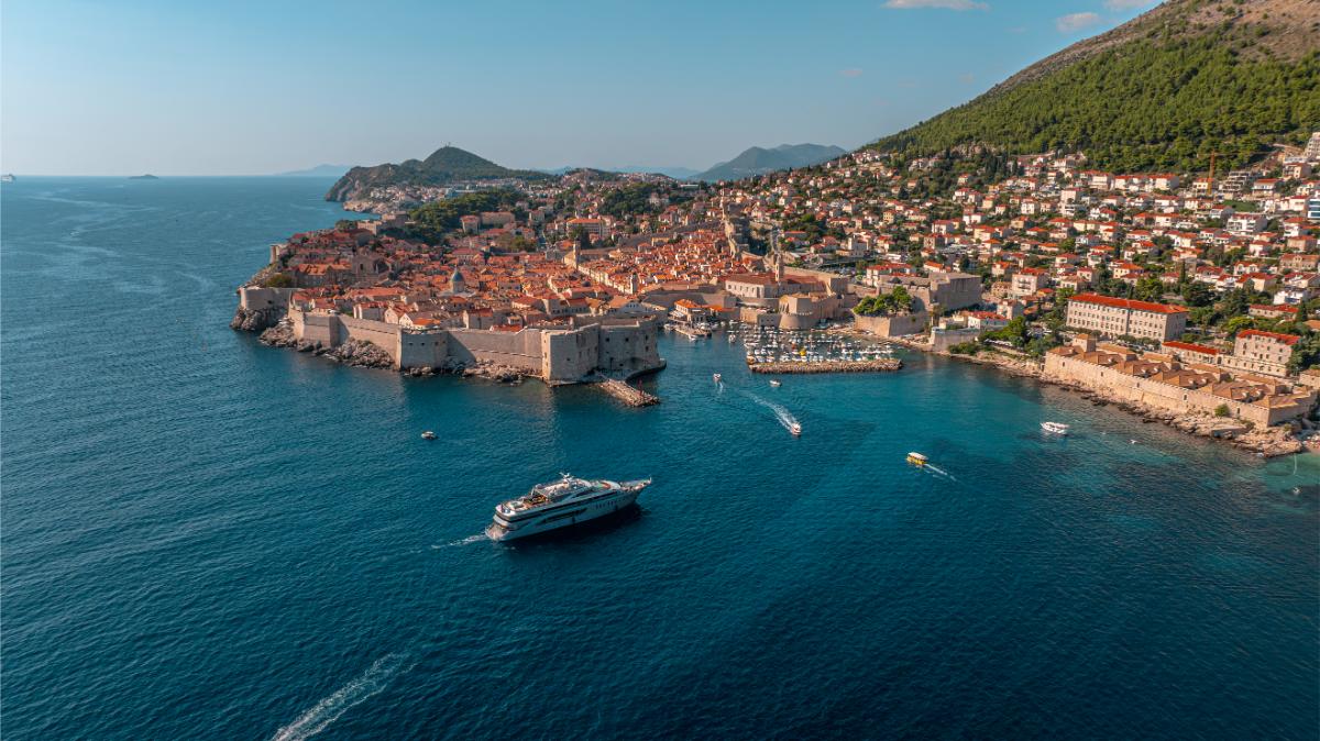 Luftaufnahme einer historischen kroatischen Küstenstadt mit roten Dächern und Luxusyachten im Hafen