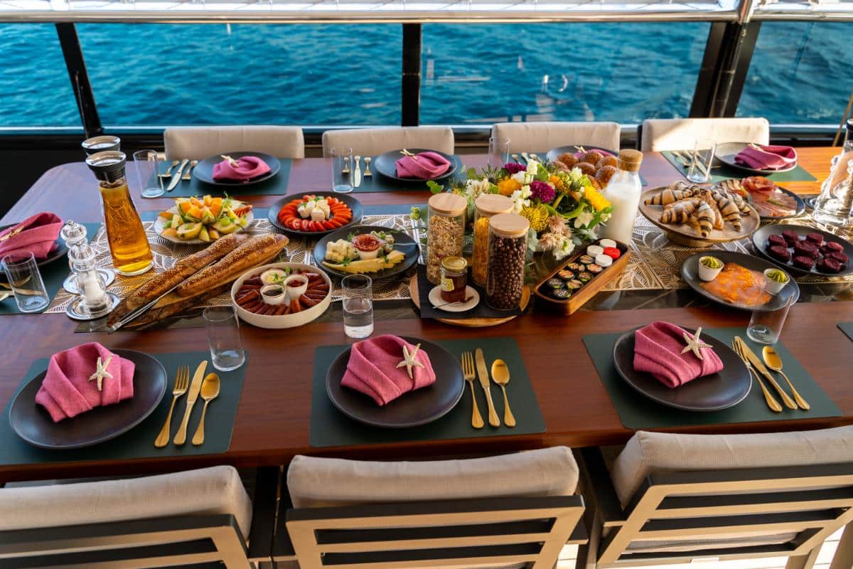 Gedeckter Gourmet-Tisch mit frischen Speisen Obst und Wein an Bord der Luxusyacht Freedom