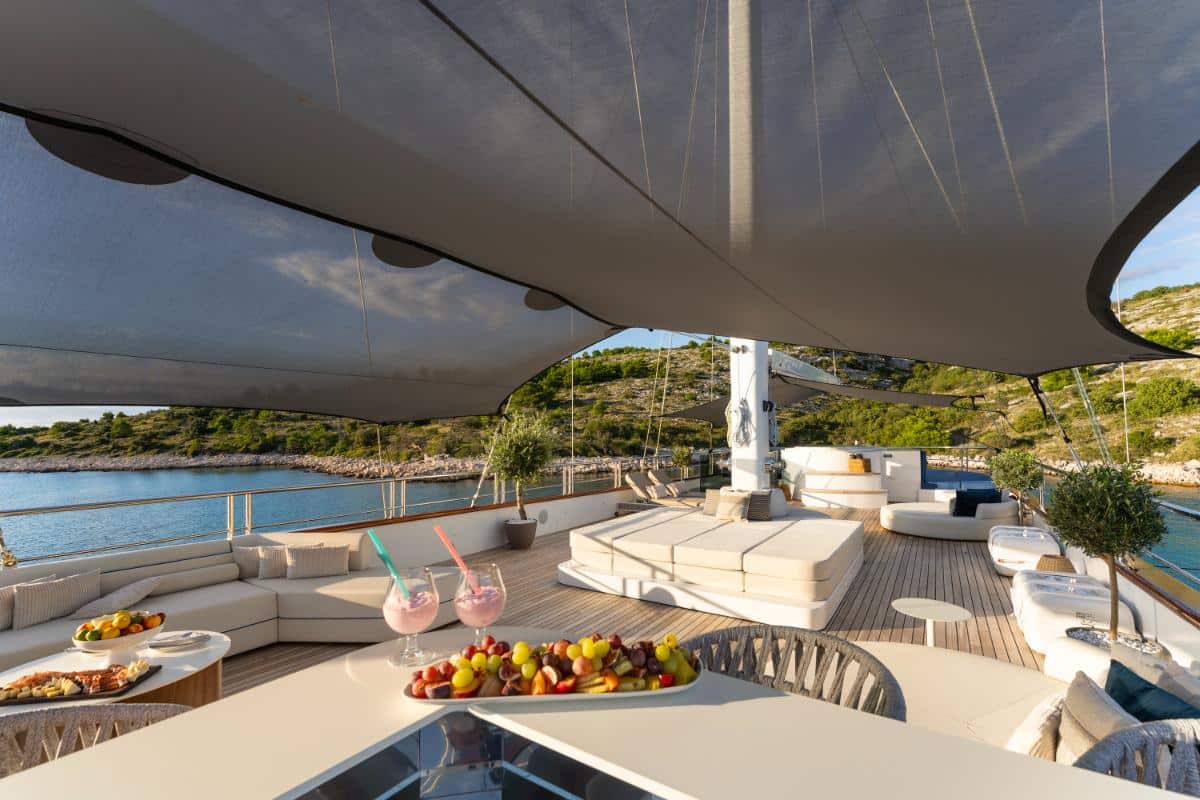 Sonnendeck der Luxusyacht Maxita mit weißen Kissen Obstplatte und türkisfarbenem Meer