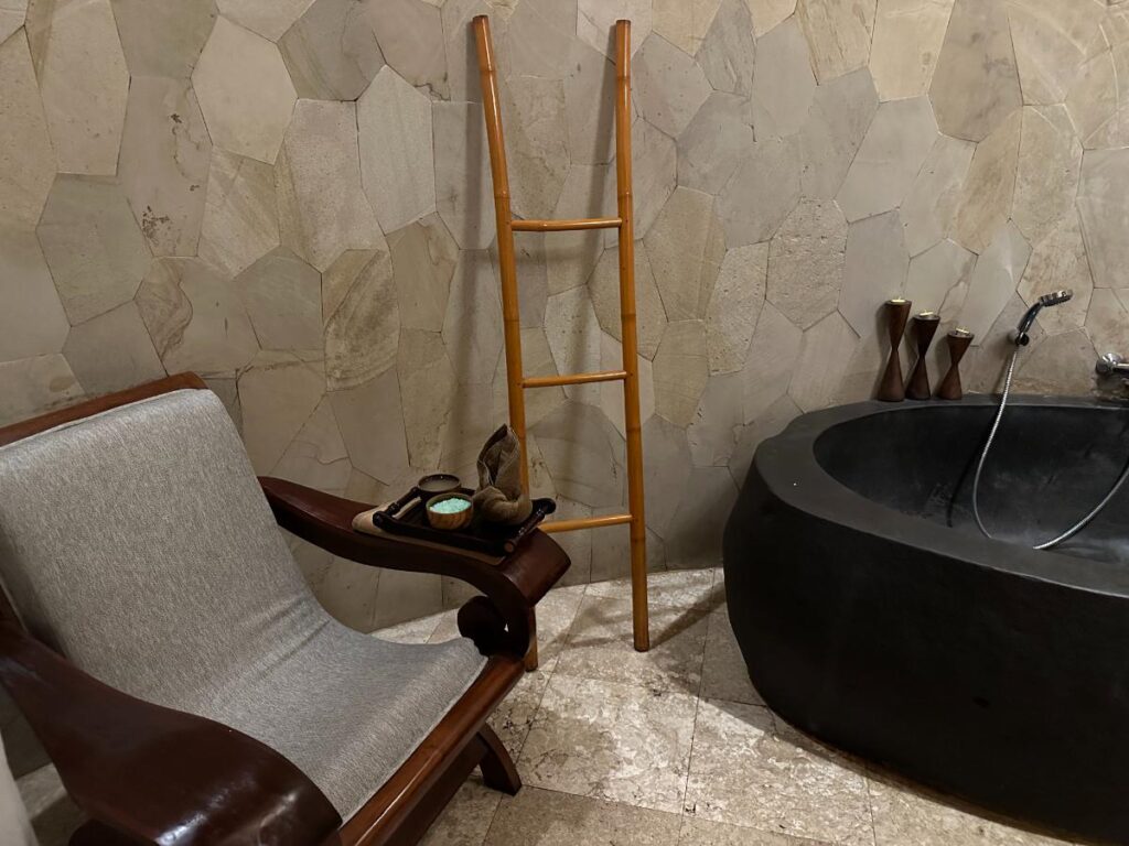 Spa-Massage-Behandlungsraum der Munduk Moding Plantation Bali mit gepolsterter Behandlungsliege und steinfarbenem Interieur