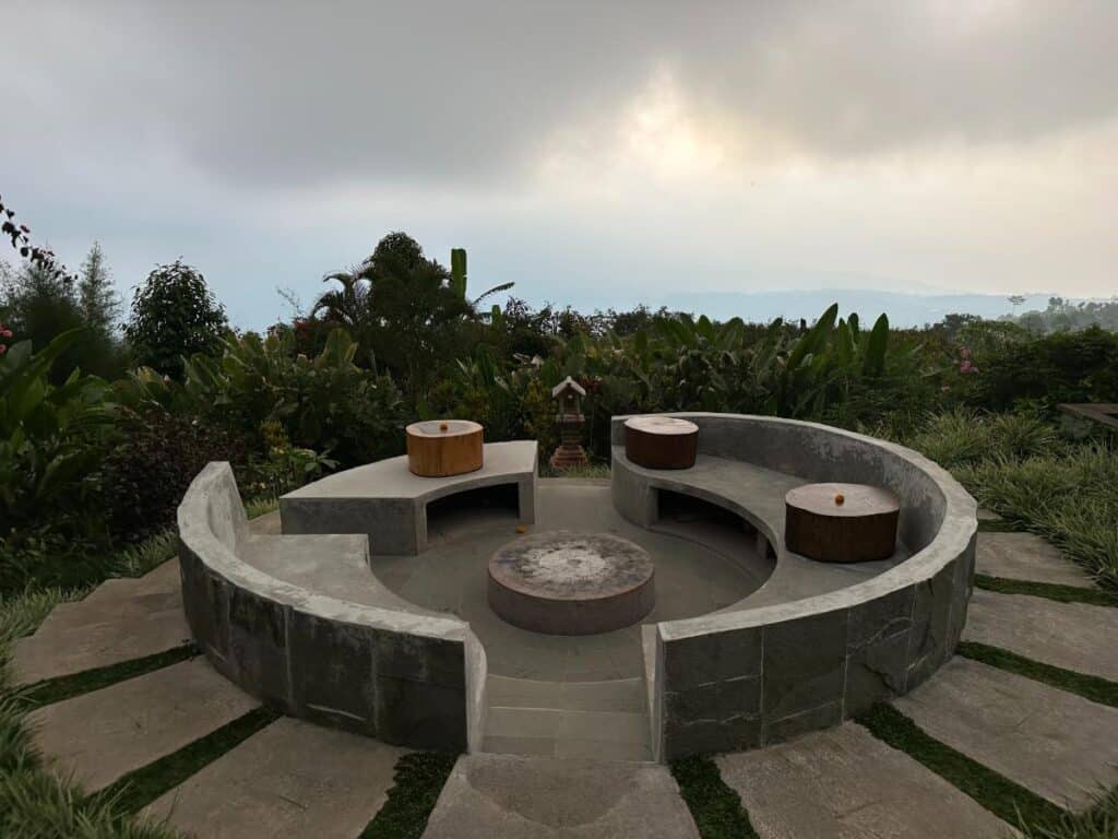 Rundes Steinwasserspiel und Feuerstelle im Freien der Munduk Moding Plantation Bali umgeben von üppiger Gartenbepflanzung