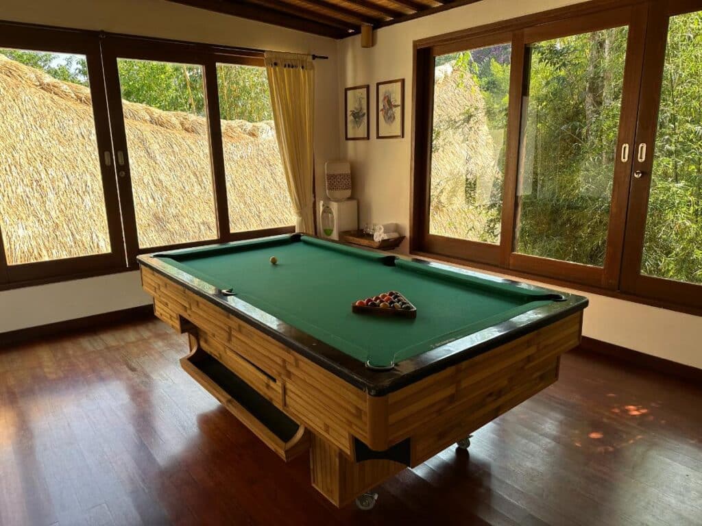 Billardraum der Munduk Moding Plantation Bali mit Billardtisch in voller Größe und Hochlandgartenblick durch Glasfenster