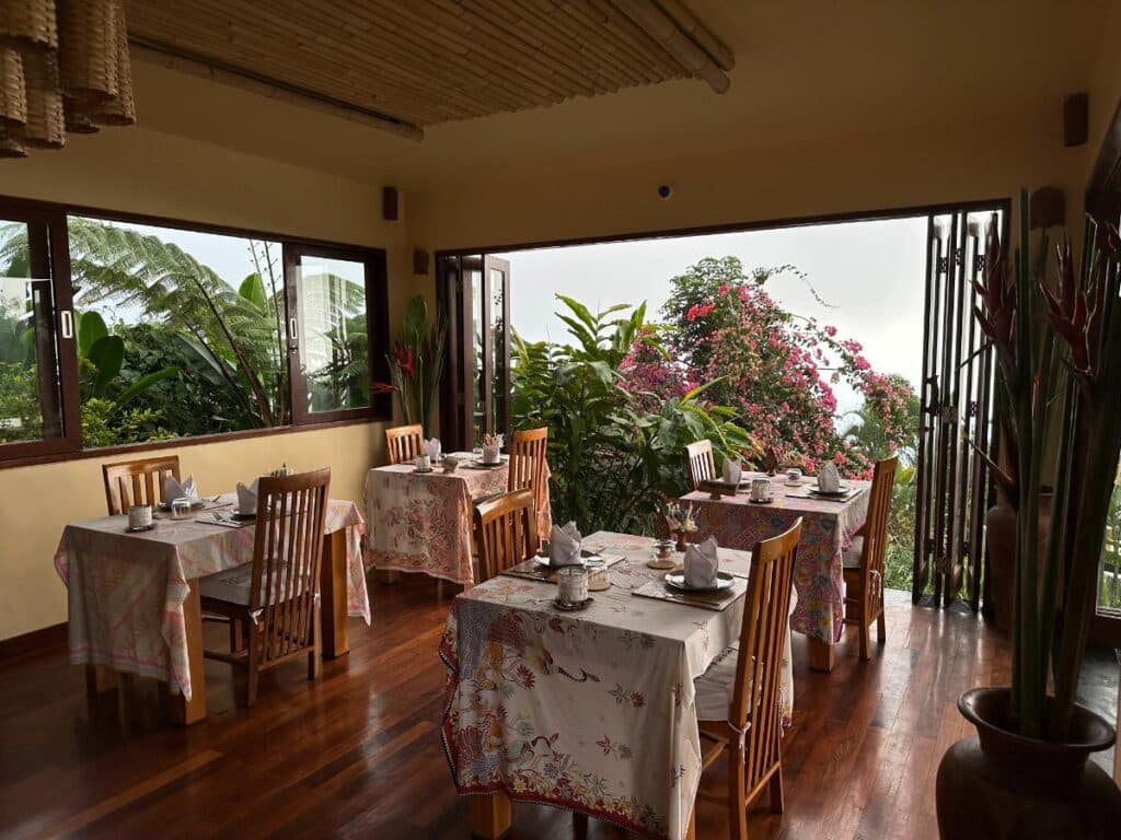 Frühstücksbereich im Restaurant der Munduk Moding Plantation Bali mit offenem Gartenblick und farbenfroher Bougainvillea