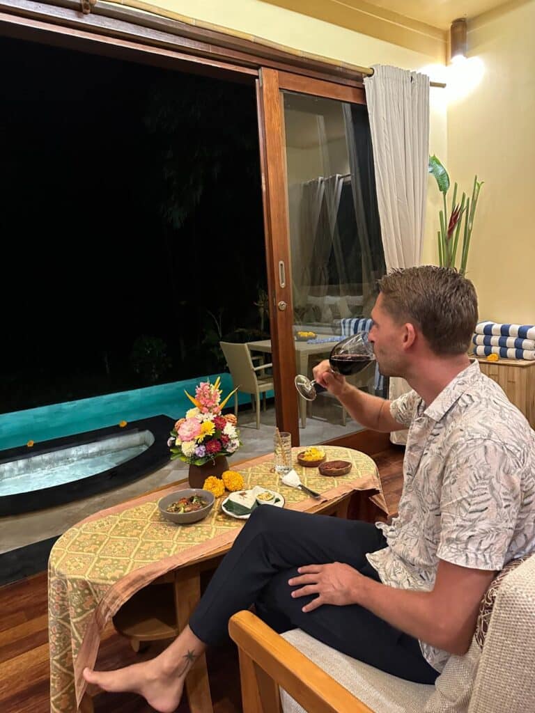 Entspannte Abendszene in der Munduk Moding Plantation Bali mit Gast bei einem Glas Wein am privaten Pool im Indoor-Outdoor-Bereich