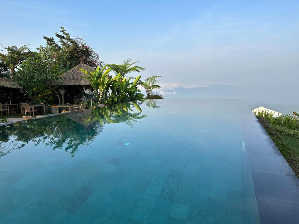 Rand des Infinity-Pools der Munduk Moding Plantation Bali, der nahtlos mit dem bewölkten Hochlandhimmel über Bali zu verschmelzen scheint