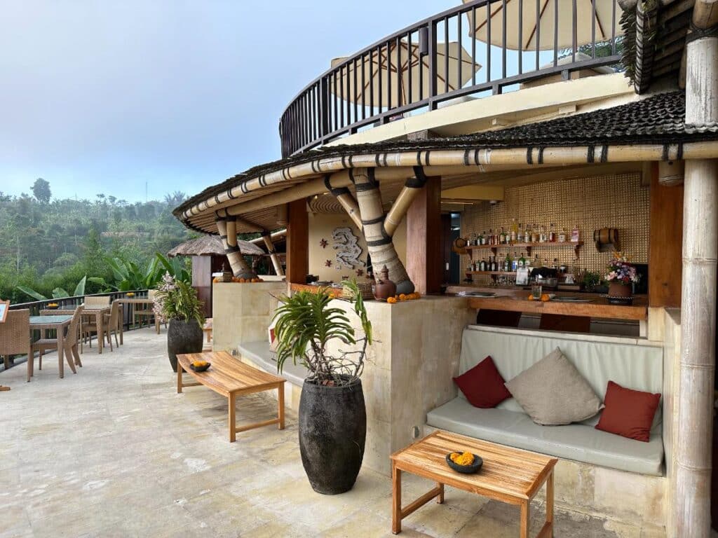 Außenansicht der Poolbar der Munduk Moding Plantation Bali mit geschwungener Steinarchitektur und legeren Loungesitzen
