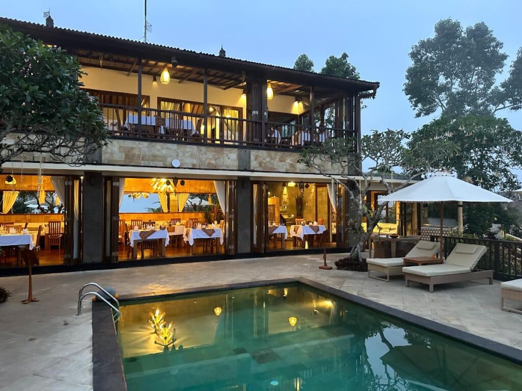 Hauptgebäude der Munduk Moding Plantation Bali nachts beleuchtet mit Poolterrasse und Restaurant sichtbar vom Resortgelände