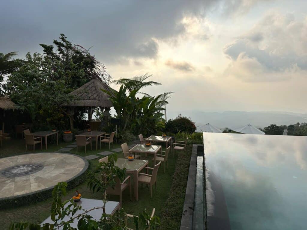 Resortgelände-Terrasse der Munduk Moding Plantation Bali zur goldenen Stunde mit strohgedecktem Bale-Pavillon und Blick auf den Infinity-Pool
