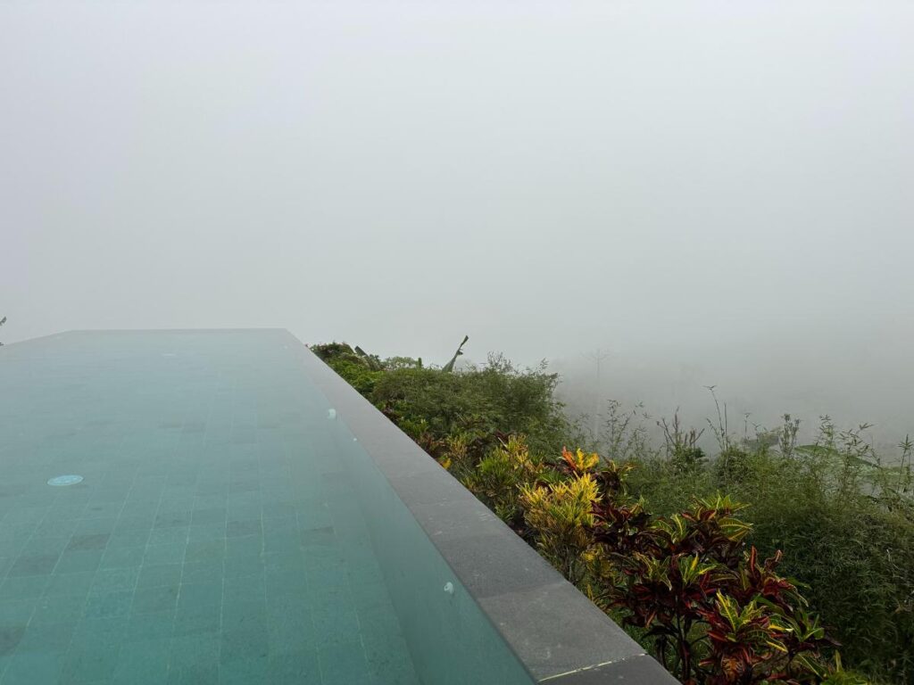 Nebliges Wolkenpanorama vom Rand des Infinity-Pools der Munduk Moding Plantation Bali mit Blick über das Blätterdach des Hochlands