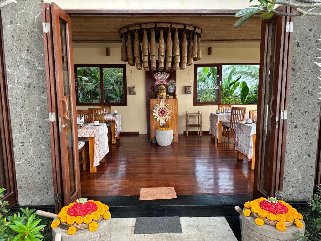 Restauranteingang der Munduk Moding Plantation Bali mit traditionellem Bambusrohr-Gong und balinesischen Blumenopfergaben