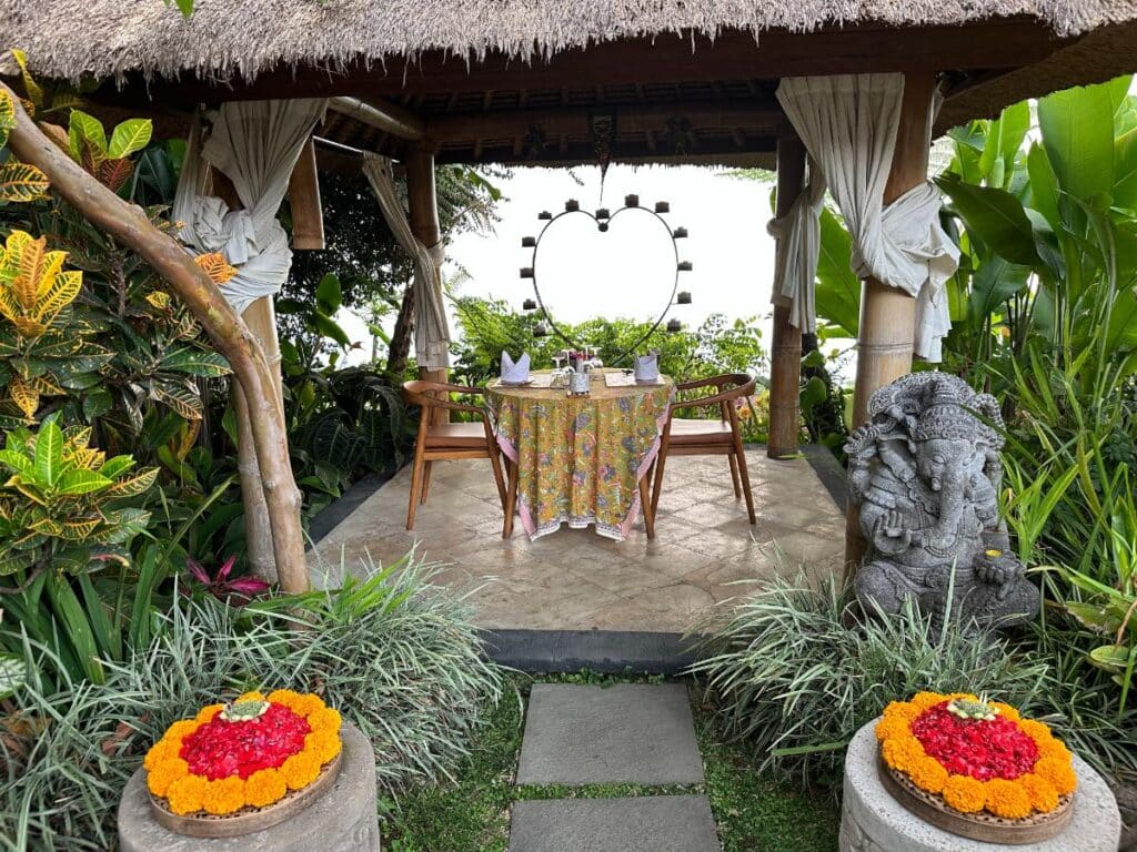 Privater romantischer Abendessen-Pavillon der Munduk Moding Plantation Bali mit Herzkandelaber, Ganesha-Statue und Blütenblatt-Opfergabe