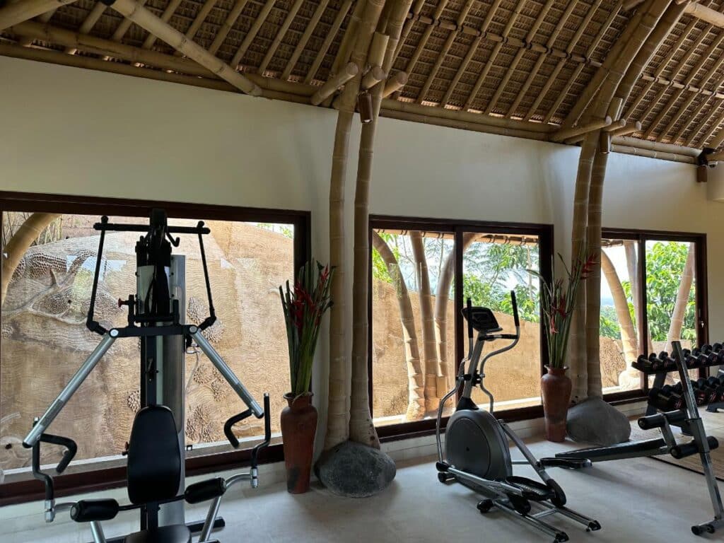 Fitnessraum-Interieur der Munduk Moding Plantation Bali mit vollständiger Ausstattung unter einem traditionellen strohgedeckten Hochdach-Pavillon