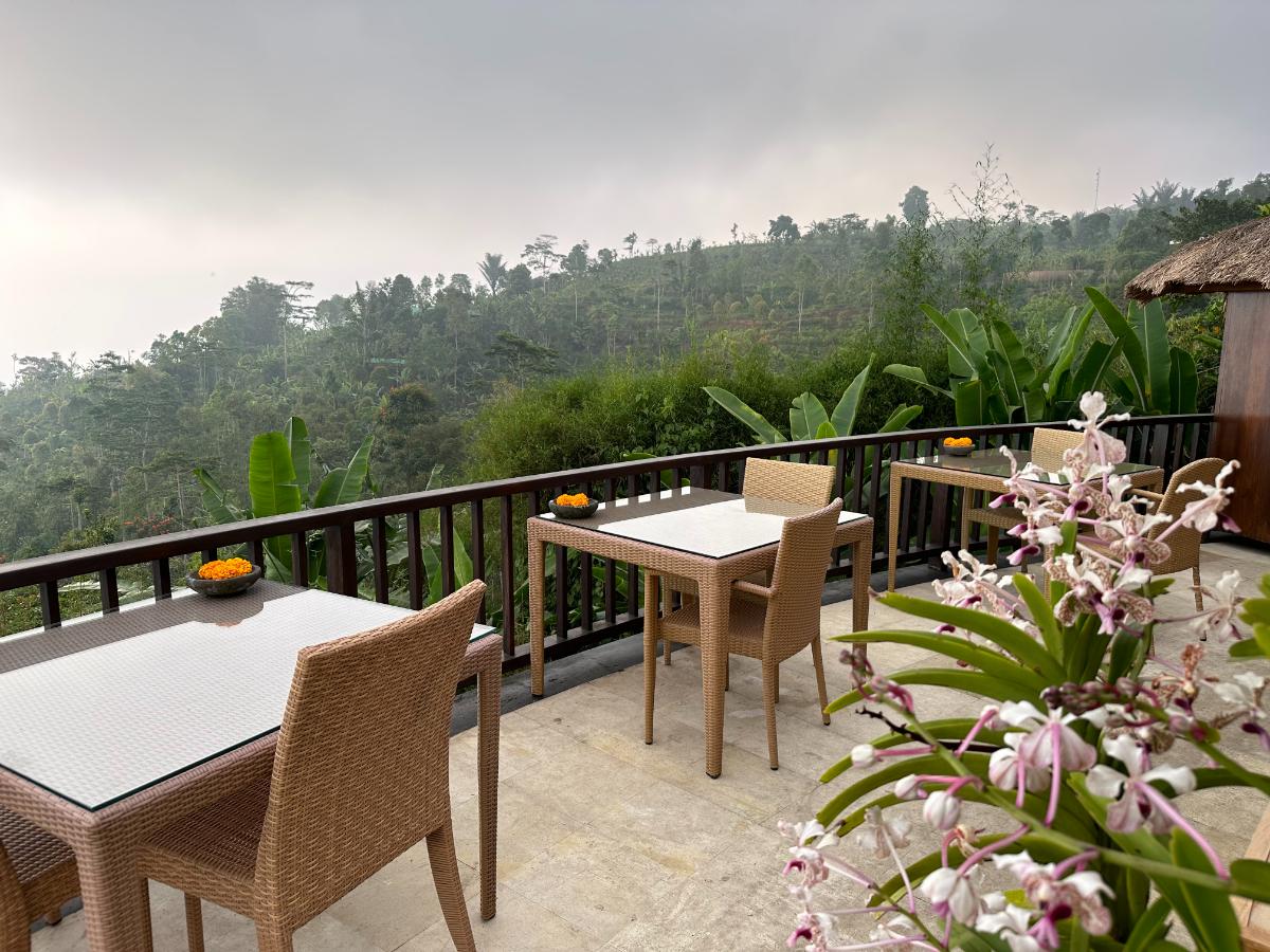 Whirlpool im Freien auf der Hügelkuppe der Munduk Moding Plantation Bali mit badendem Gast, umgeben von wolkiger Hochlandlandschaft und Rattanliegen