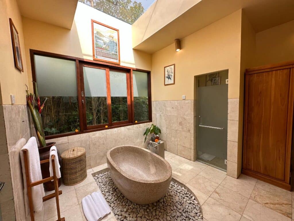 Offenes Badezimmer-Interieur der Villa in der Munduk Moding Plantation Bali mit freistehender Vulkanstein-Badewanne und Steinfliesenwänden