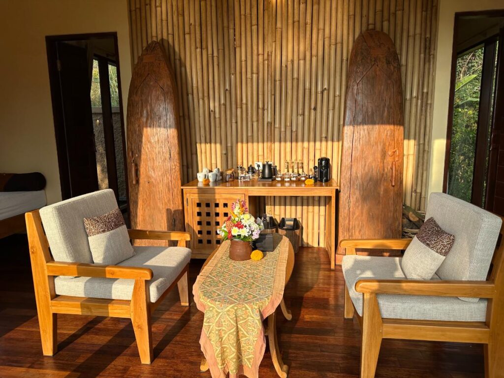 Weitwinkelansicht des Villa-Wohnzimmers in der Munduk Moding Plantation Bali mit Bambus-Wandverkleidung, Holzmöbeln und Schachspiel