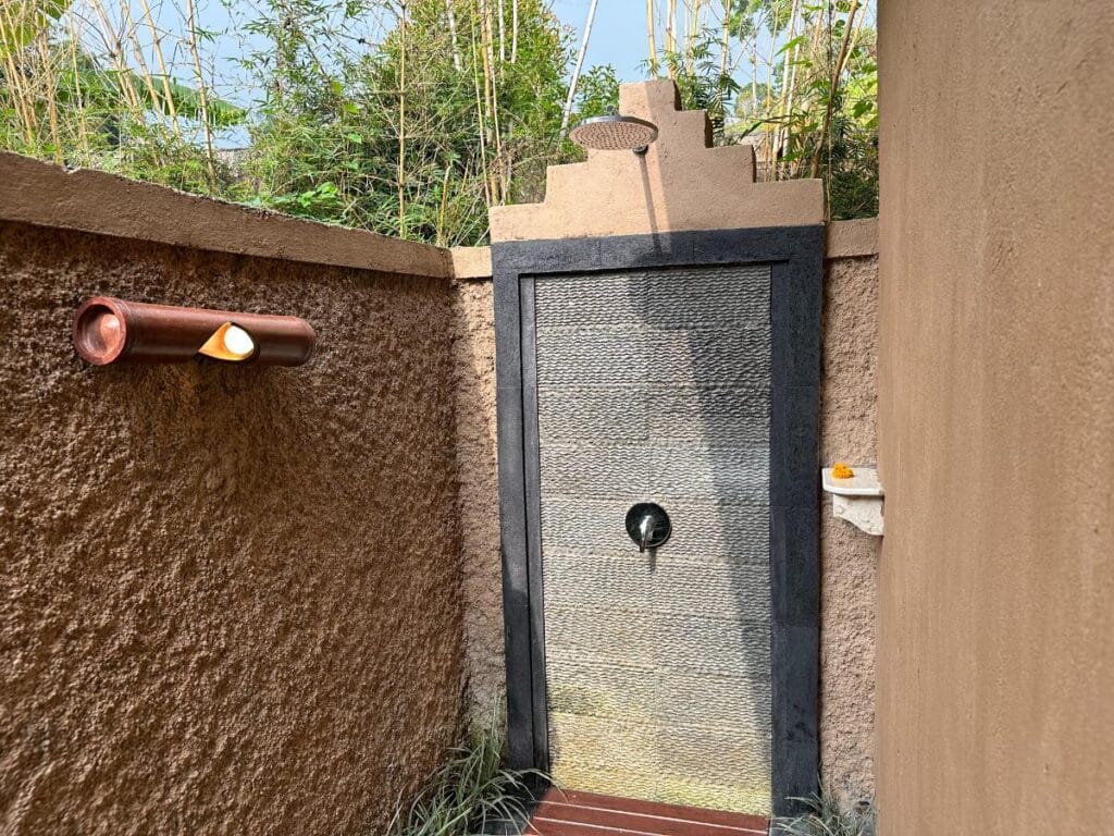 Regendusche im Freien mit Steinmauern in der Munduk Moding Plantation Bali Villa mit tropischem Gartenblick und natürlichem Licht