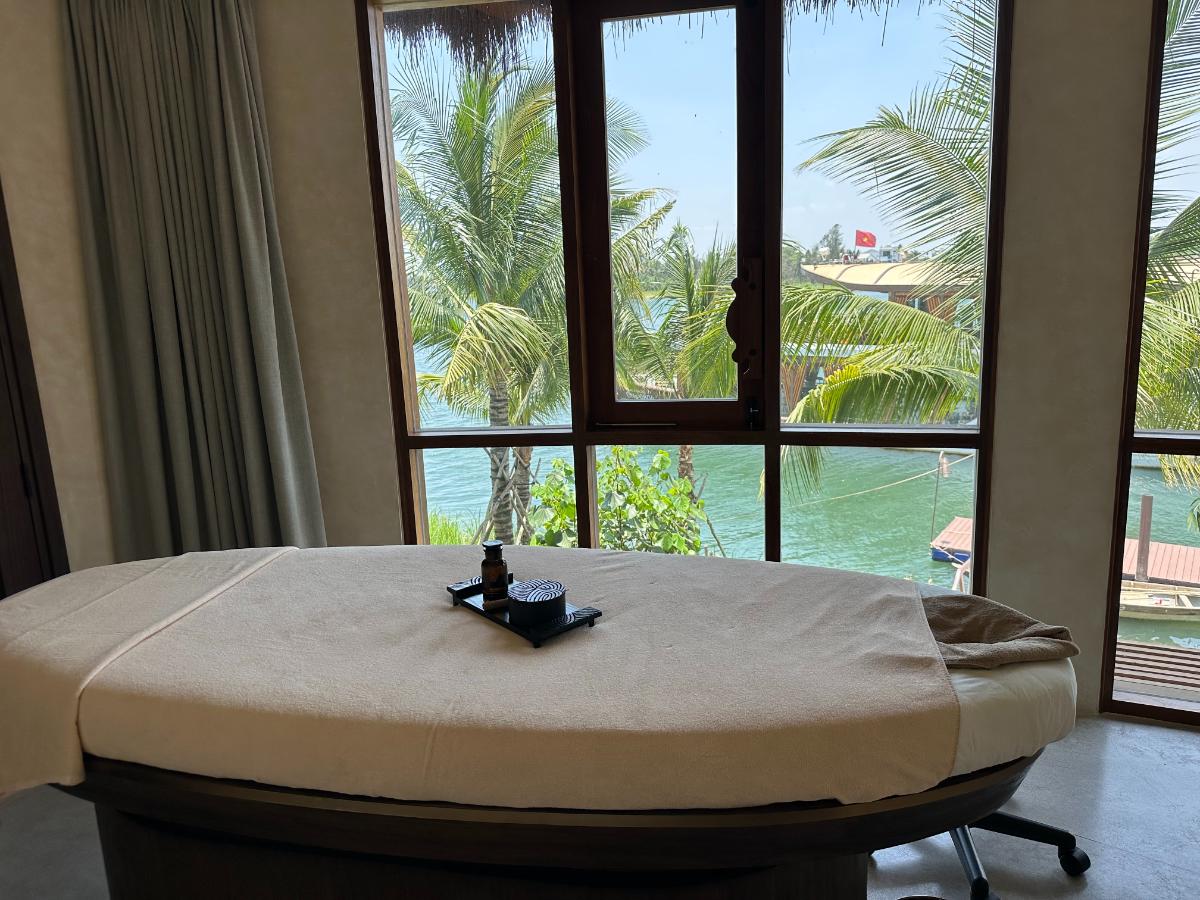 Spa relaxation daybed facing floor-to-ceiling Thu Bon River windows, Namia River Retreat, Hoi An, Vietnam