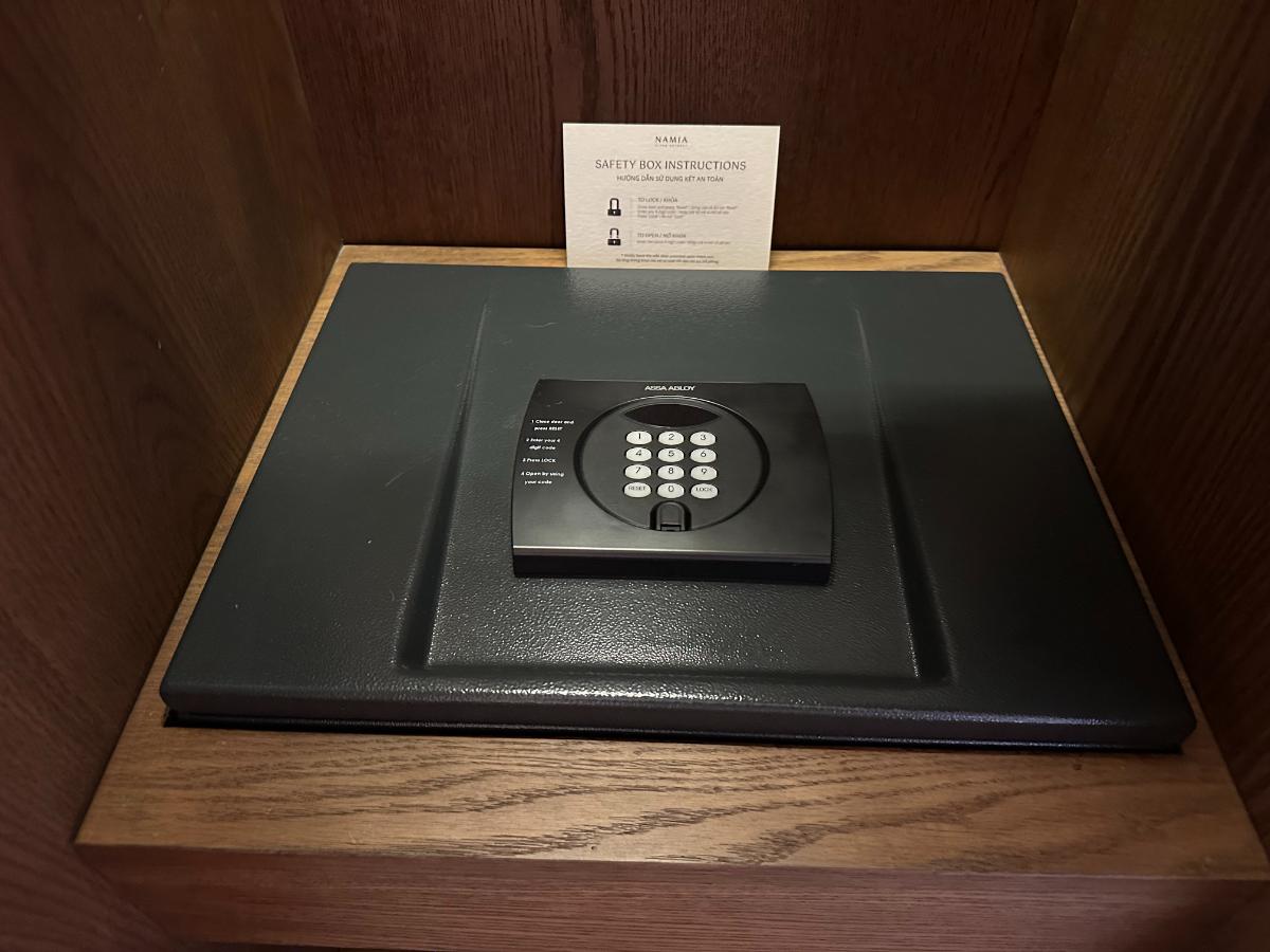 In-room digital safe with welcome card on a wooden shelf, Namia River Retreat, Hoi An, Vietnam