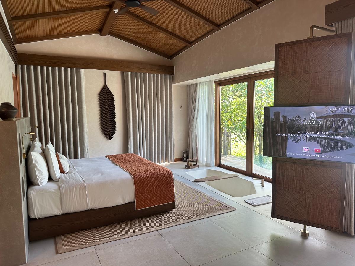 Bedroom and living area divided by rotating screen, pool villa interior, Namia River Retreat, Hoi An, Vietnam