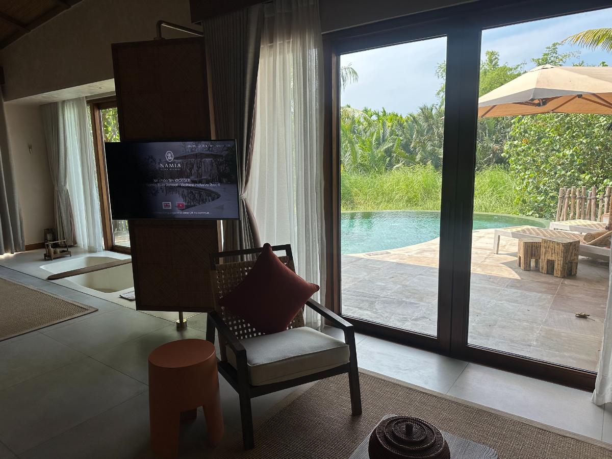 Living room with rotating TV partition and pool view glass wall, pool villa, Namia River Retreat, Hoi An, Vietnam