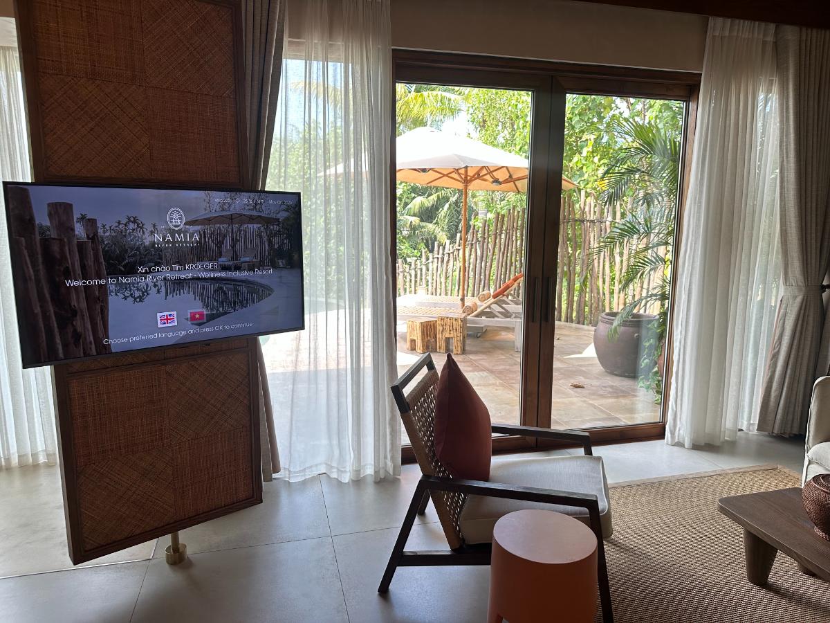 Villa living area with floor-to-ceiling glass doors opening to the private pool, Namia River Retreat, Hoi An, Vietnam