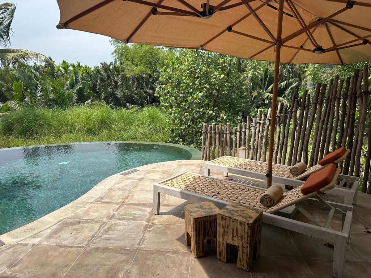 Sun loungers under a parasol beside the private villa pool, Namia River Retreat, Hoi An, Vietnam