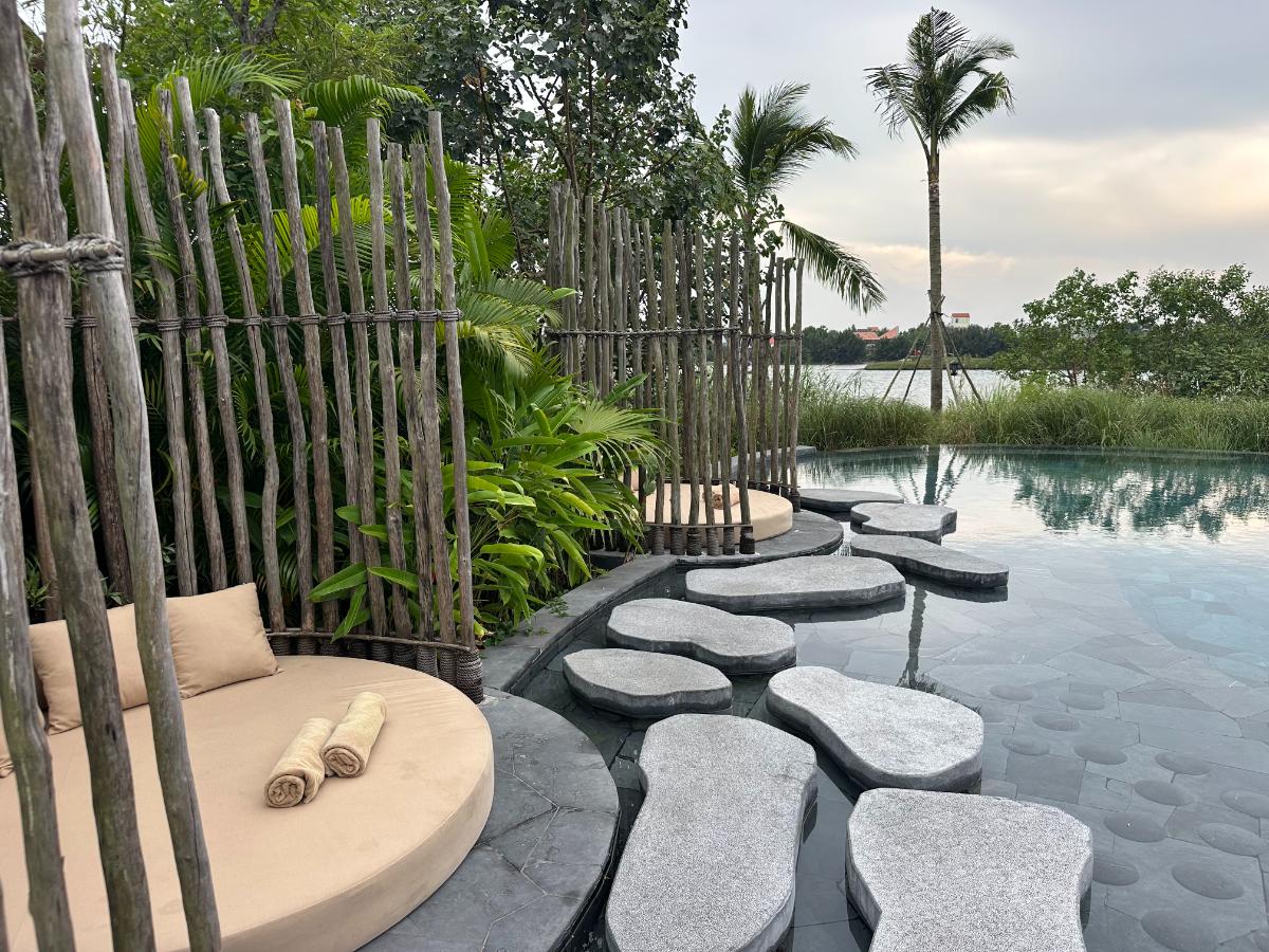 Pool stepping stones beside a bamboo privacy screen at sunset, Namia River Retreat, Hoi An, Vietnam