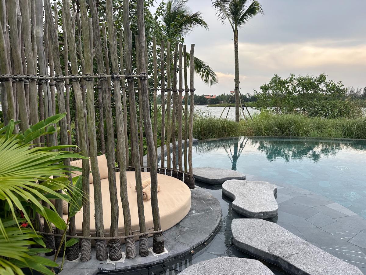 Bamboo screen island in the main pool framing the Thu Bon River, Namia River Retreat, Hoi An, Vietnam