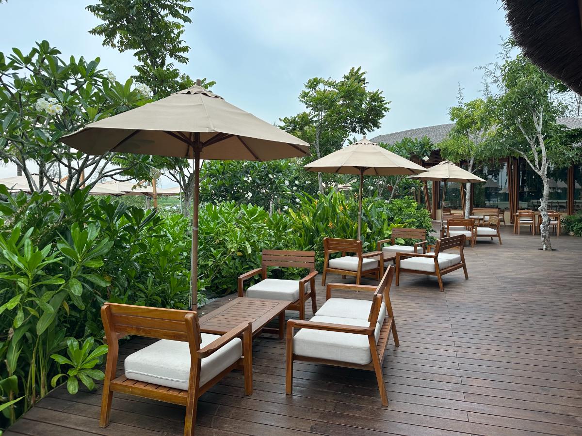 Main pool deck with timber loungers and umbrellas framed by gardens, Namia River Retreat, Hoi An, Vietnam