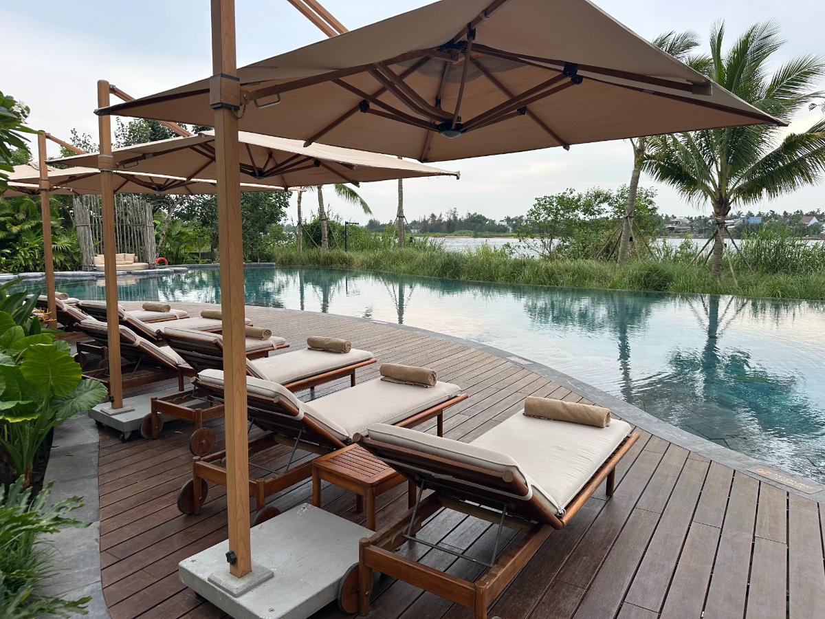 Daybed loungers along the infinity pool with the Thu Bon River beyond, Namia River Retreat, Hoi An, Vietnam