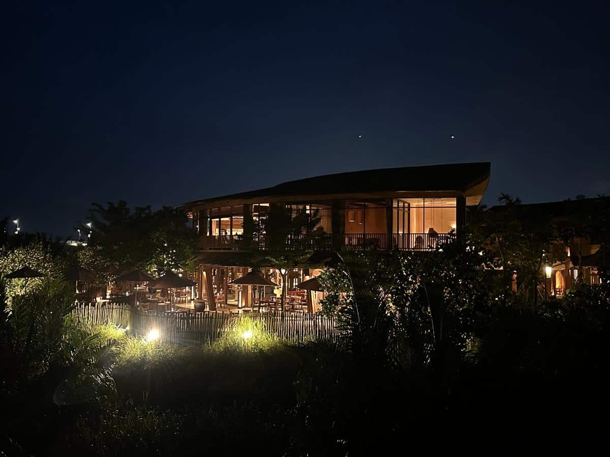 Pool villa exterior lit at night across a lotus pond, Namia River Retreat, Hoi An, Vietnam