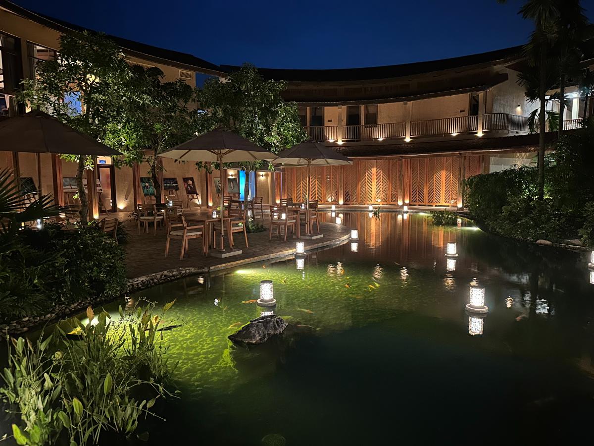 Curved restaurant pavilion with floating lanterns on the pond at night, Namia River Retreat, Hoi An, Vietnam
