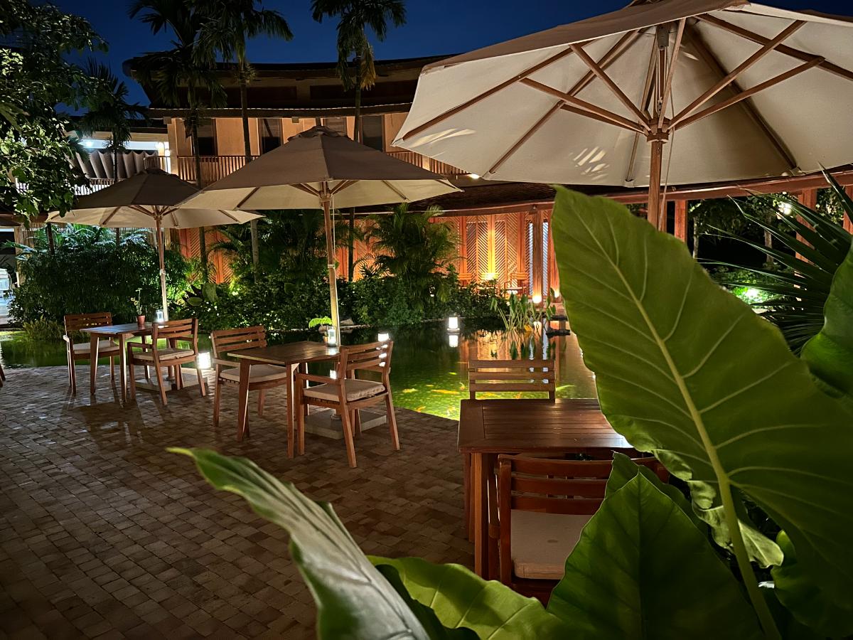 Outdoor restaurant terrace with parasols and warm lighting at night, Namia River Retreat, Hoi An, Vietnam