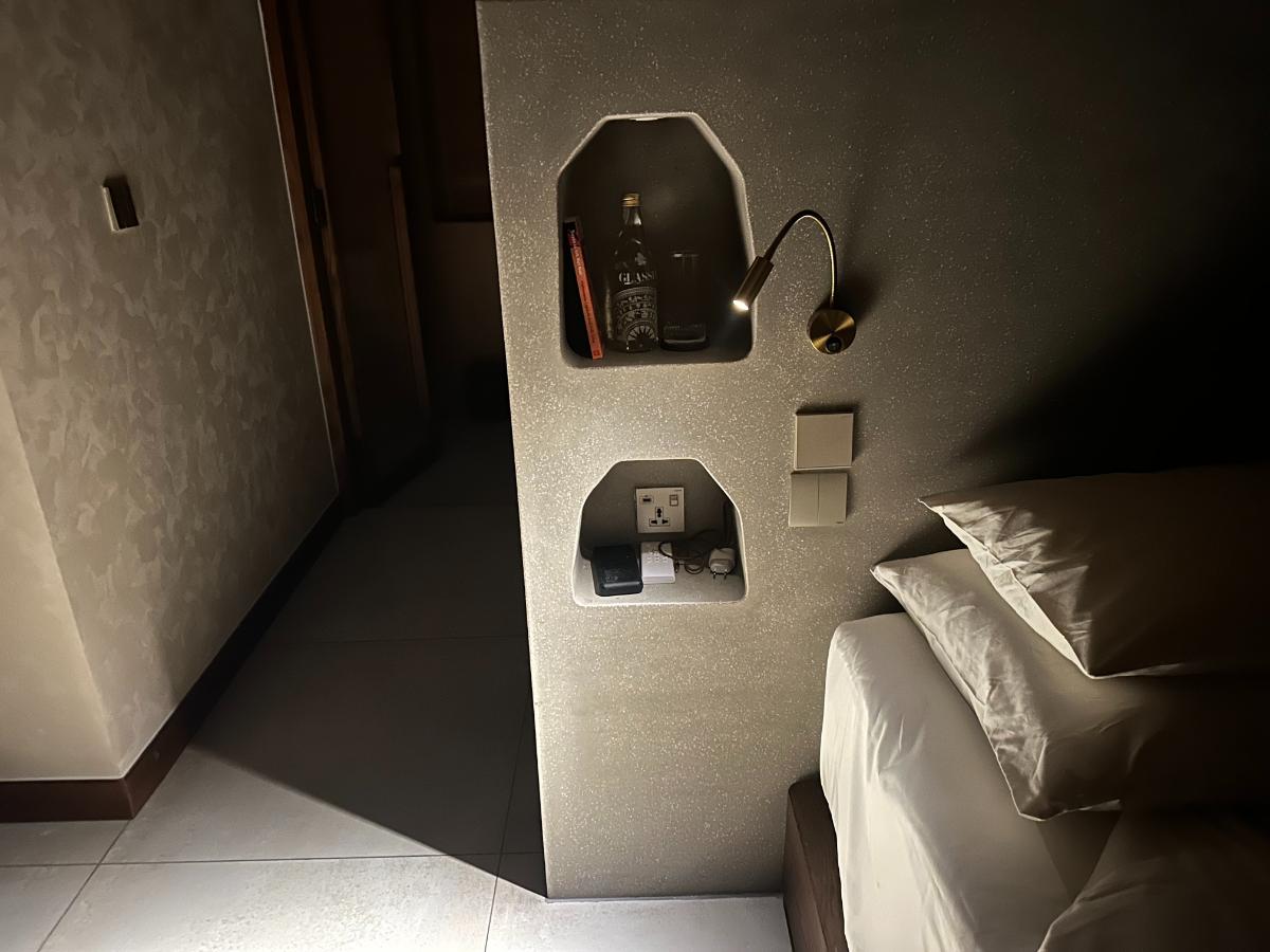 Bedside reading lamp and wall niche in the pool villa bedroom, Namia River Retreat, Hoi An, Vietnam