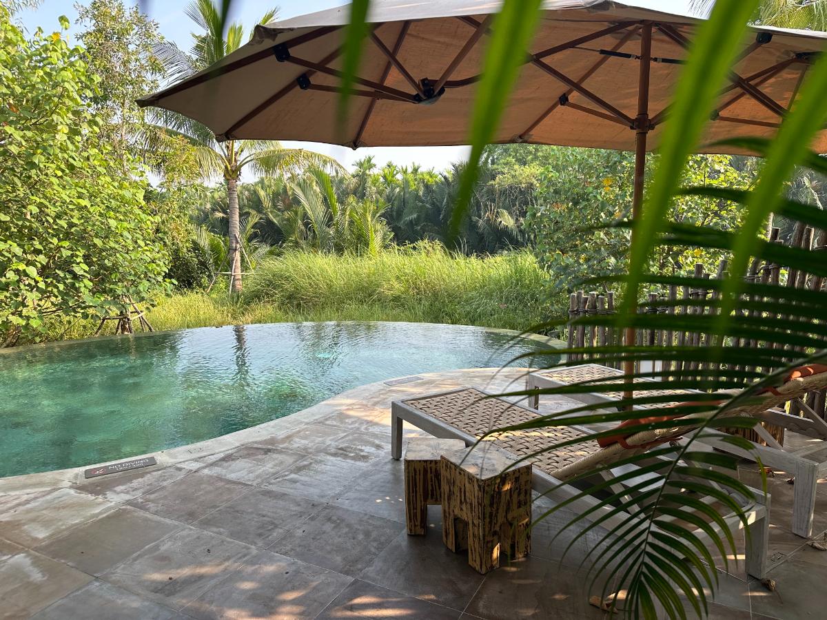 Private plunge pool with bamboo loungers and parasol at the pool villa, Namia River Retreat, Hoi An, Vietnam