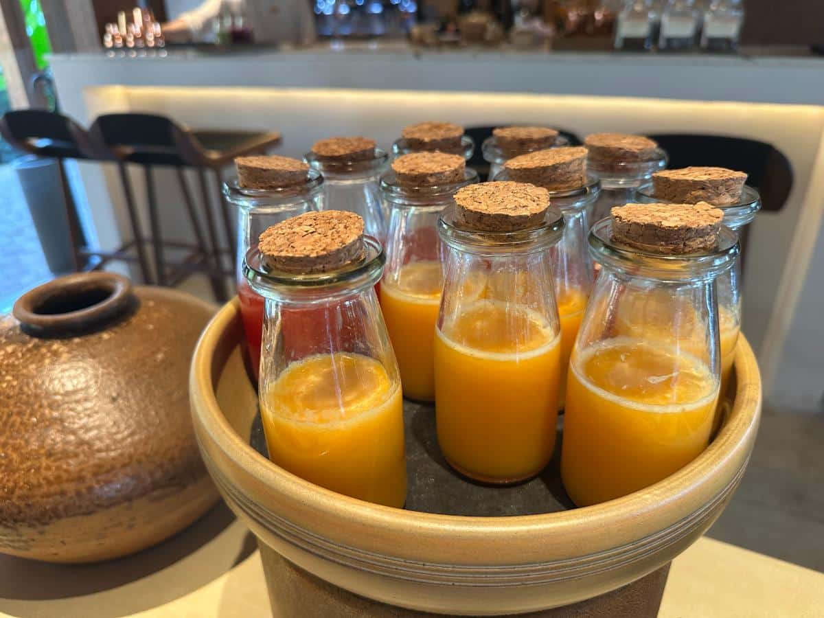 Fresh-pressed orange juice bottles with cork stoppers at breakfast, Namia River Retreat, Hoi An, Vietnam