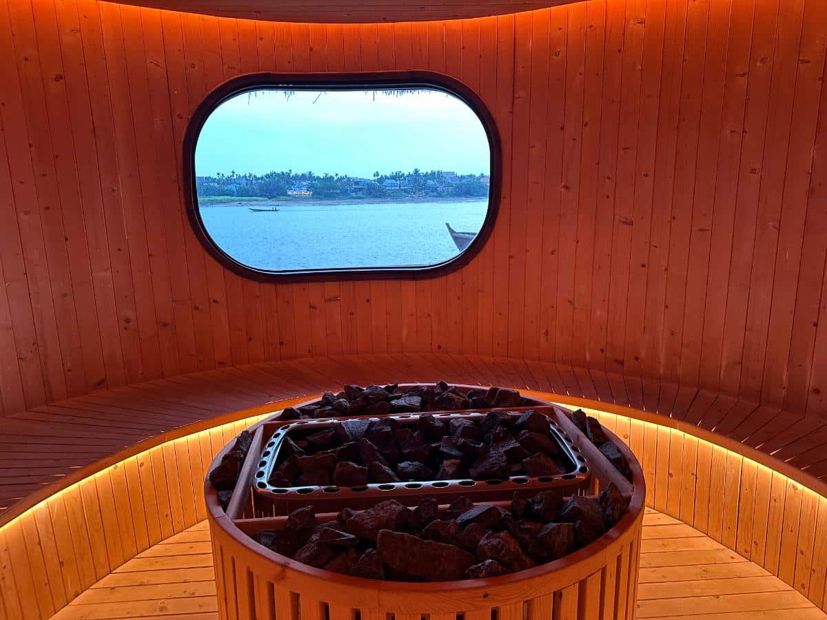 Sauna interior with hot stone heater and oval river-view window, Namia River Retreat, Hoi An, Vietnam